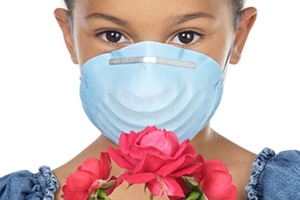 Immagine di una bimba con la mascherina che tiene in mano dei fiori Immagine di una bimba con la mascherina che tiene in mano dei fiori